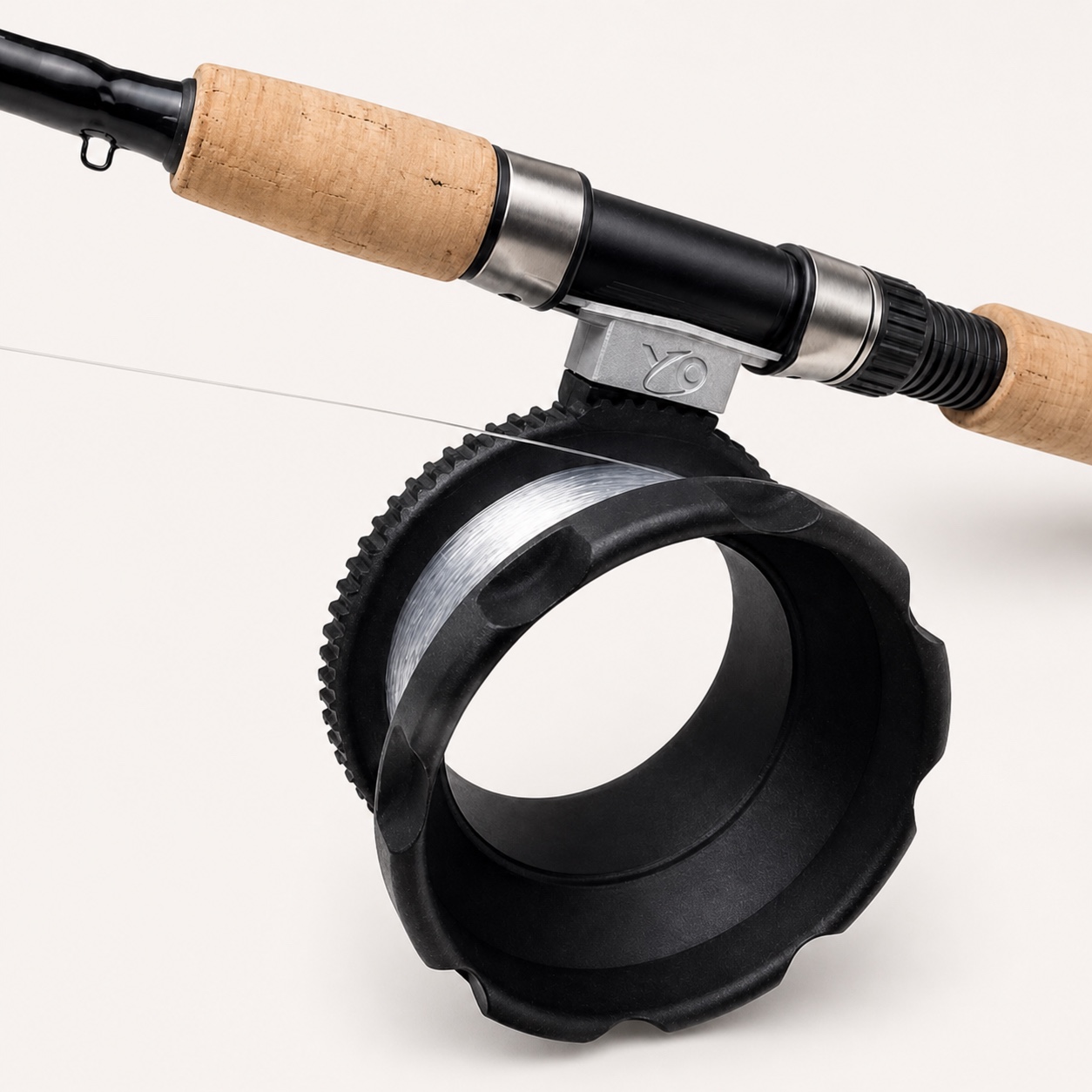 Close product view of the black circular YO Reel, silver swivel mount, and cork-handled rod